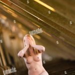 Healthy lifestyle and well-being: A naked nude young blonde woman sitting facing the camera with her hands covering her face exhibitionist exhibitionism Stock Photo