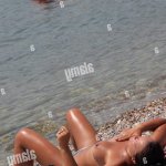 Woman sunbathing on the beach naked while a man floating on air mattress. Budva. Montenegro Stock Photo